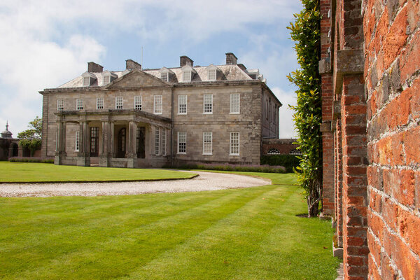 Английский загородный дом в сельской местности с большим лавочником и обширным садом с орнаментами