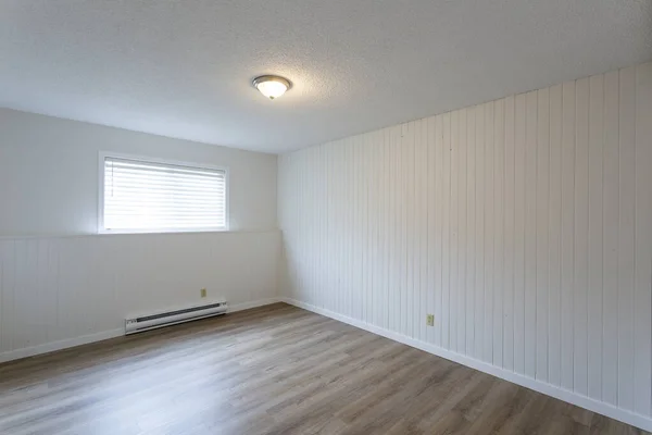 Interior of empty renovated apartment condo rental unit with white walls and new hard wood vinyl laminate flooring.