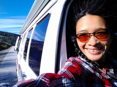 Yeni nesil, Asyalı bir kadın yaz sezonunda Kanada 'nın Britanya Kolumbiyası' ndaki Okanagan Vadisi 'nde bir karavan aracından selfie çekiyor..