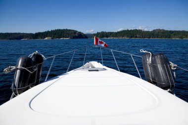 Desolation Sound, British Columbia, Kanada 'daki küçük bir teknenin baş omuzluğundan sakin deniz manzarası. Açık mavi su parlak bir gökyüzünün altında parlıyor..
