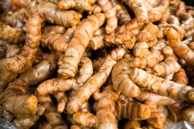 Whole organic turmeric root displayed at a local market, showcasing its vibrant color and unique shape, perfect for cooking and health benefits.