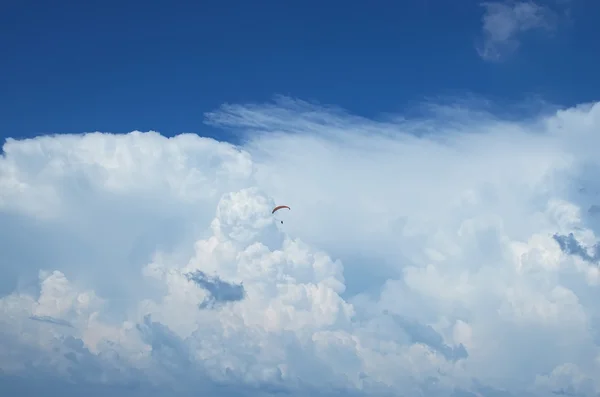 En man flyger en paraglider på en bakgrund av stora vita moln — Stockfoto