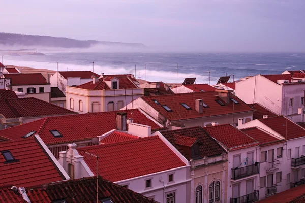 Mañana en la costa atlántica. Nazare. Portugal. Lluvia de lluvia no pasa, las grandes olas están rodando a la orilla. Niebla viene del océano . — Foto de Stock