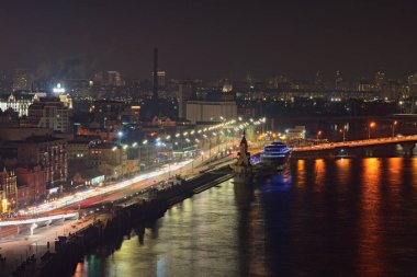 Gece boyunca Kyiv 'in manzaralı görüntüsü. Antik Podil ve Kyiv nehir limanının gece ışıkları manzarası. Şehrin güzel bir aydınlanması. Tepeden hava manzarası. 