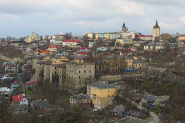 Renkli kiremit çatılı binaların bulunduğu yerleşim bölgesinin manzarası. Tepedeki Kamianets-Podilskyi 'nin tarihi binaları. Bulutlu kış günü. 