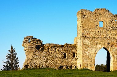 Antik Krements şatosunun kalıntılarının resimli manzarası. Mavi gökyüzüne karşı savunma duvarı ve kale kulesinin bir parçası. Arka plandaki eski çam ağacının tepesinde. Kremenetler, Ukrayna.