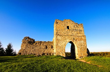 Eski Krements şatosunun kalıntılarının geniş açılı manzarası. Mavi gökyüzüne karşı savunma duvarı ve kale kulesinin bir parçası. Arka plandaki eski çam ağacının tepesinde. Kremenetler, Ukrayna.