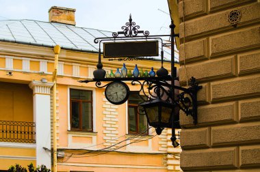 Chernivtsi, Ukrayna-13 Mayıs 2021: Binanın köşesindeki sahne reklam tabelası. Sokak saati ve renkli şişelerle süslenmiş işaret levhasının ayrıntılı görüntüsü. Arka plandaki bina cephesi..