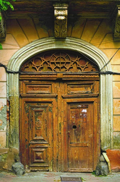 Detailed view of ancient street double door. Old wooden doors with peeling paint. Ancient ornamental wooden door. Wood texture. Grunge backdrop. Ancient building facade in Chernivtsi, Ukraine.