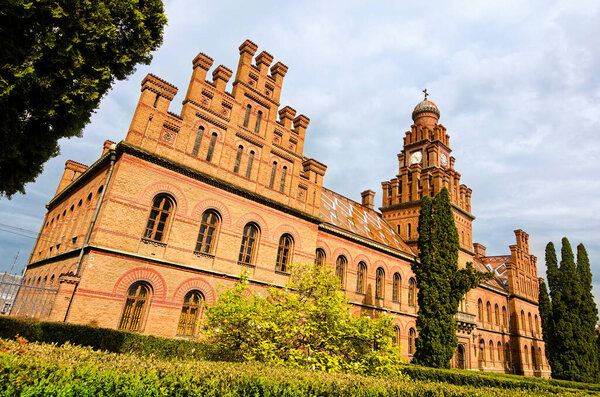 Classic wide-angle landscape view of medieval brown brick building with clock tower and inner yard in Chernivtsi University. UNESCO World Heritage Site. Travel and tourism concept.