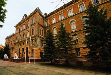 Chernivtsi, Ukrayna - 13 Mayıs 2021: İki beyaz aslan heykeli olan antik binanın geniş açılı manzarası. Grushevsky Caddesi, 1 numaradaki Chernivtsi Bölge Yönetimi.