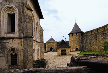 Astonishing landscape view of courtyard with ancient stone buildings in the medieval castle. High stone wall with tower in the background. Famous touristic place and romantic travel destination.