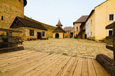 Picturesque landscape view of courtyard with ancient stone buildings in the old medieval castle. High stone wall with tower in the background. Famous touristic place and romantic travel destination.