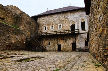 Ortaçağ şatosunda antik taş bina ile muhteşem bir avlu manzarası. Arka planda kule olan yüksek taş duvar. Ünlü turistik yer ve romantik seyahat merkezi..
