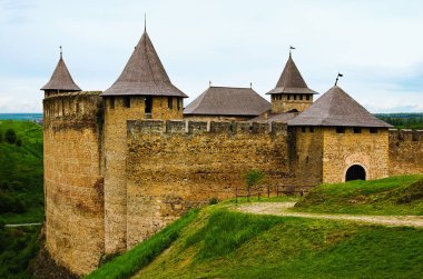 Eski şatonun güzel manzarası ve ana kapıya giden parke taşı yolu. Yeşil çimenli tepeler. Mavi gökyüzü arka planı. Ünlü turistik yer ve romantik seyahat merkezi..
