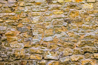 Eski taş bir duvar parçası. Güneş ışığında çok renkli büyük kaldırımlar. Ortaçağ taş duvarının kusursuz dokusu. Eski kale taşı duvar dokusu arkaplanı.