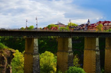 Yüksek katlı taş destekli eski gelinin detaylı görüntüsü. Nehir boyunca taş destekli köprü. Bulutlu bir arka plan. Smotrytsky Kanyonu üzerindeki Novoplanovsky köprüsünün şehir manzarası.