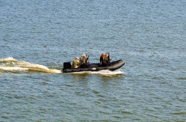 Siyah motorlu teknede silahlı ve özel teçhizatlı beş asker. Özel harekat güçleri.