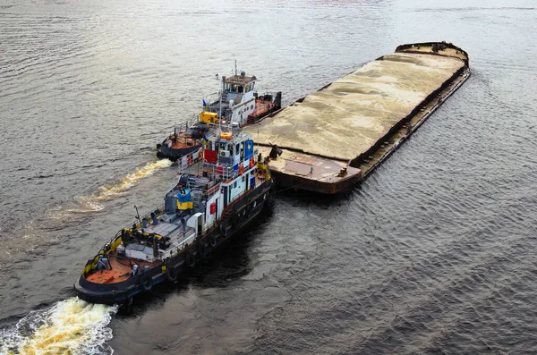 River barge loaded with sand. Landscape view of cargo ship barge loaded with sand. Top view of the barge with sand with two tugboats.