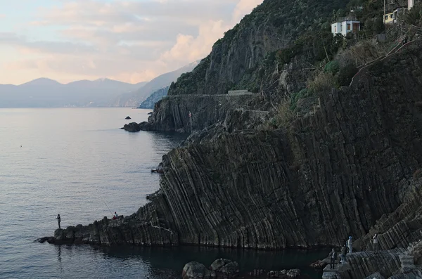 Pescador com uma vara de pesca na borda da rocha. Riomaggiore. Cinque Terre. Itália . — Fotografia de Stock