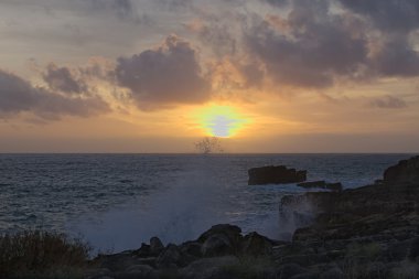 Sahilde muhteşem gün batımı. Deniz fırtınalı. Dalga üzerinde kırılıyor