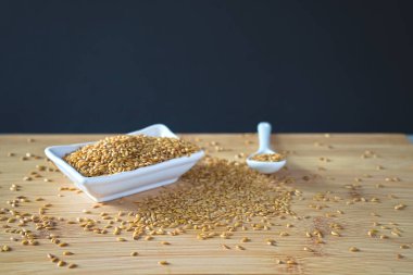 Altın susam tohumları beyaz bir kaseden yapışkan bambu tepsilerine dökülür. Sığ alan derinliği.