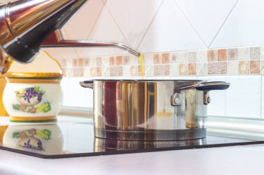 Tencereye yağ dökerek.