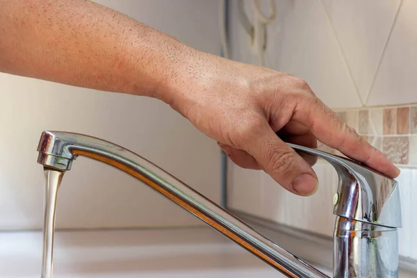 hand opening the kitchen water tap