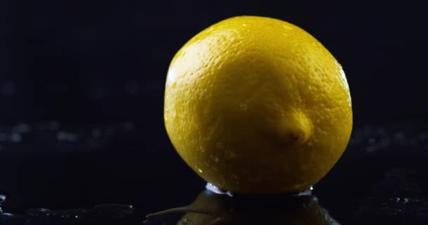 Mano para hombre gira un gran limón mojado en una mesa húmeda negro — Vídeo de stock
