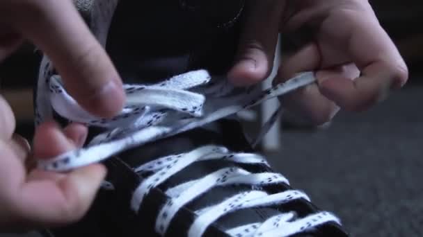 Homme noue lacets blancs sur patins noirs dans les vestiaires avec une lumière tamisée — Video
