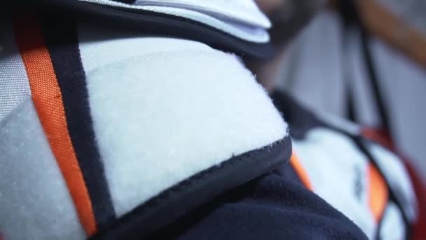 Un homme fixe un uniforme de hockey protecteur sur son épaule sur un Velcro — Video