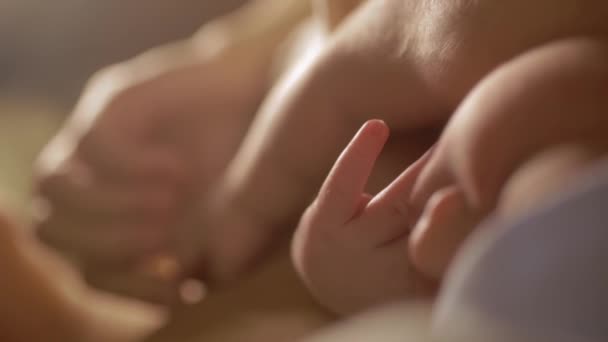 Chica joven se acuesta con el bebé y rizando la mano de los niños dormidos en su mano — Vídeo de stock