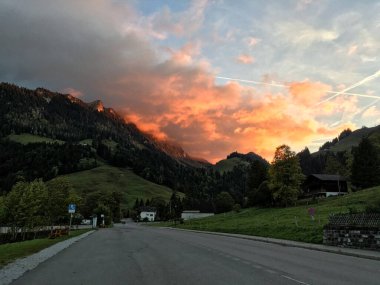 Gün batımında İsviçre dağlarının manzarası, kırmızı ışıklı bulutlu gökyüzü