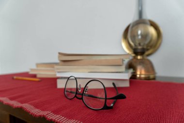 Önplanda gözlük ve arka planda bir kitap yığını