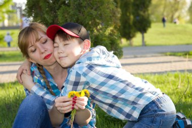Mother and son in the park on the grass clipart