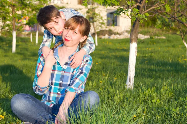 Matka a syn sedí na trávě — Stock fotografie