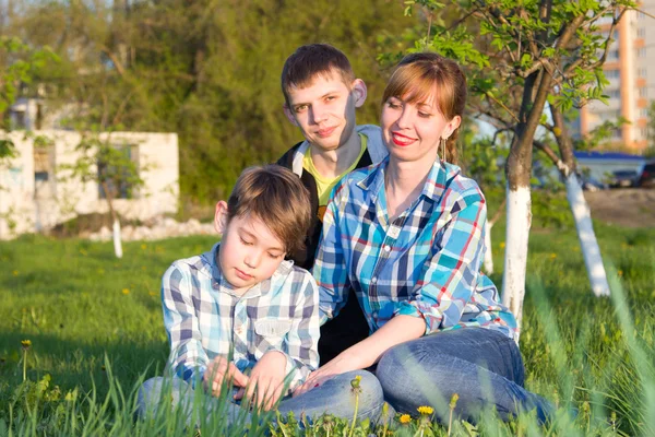 Rodina sedí na trávě v parku — Stock fotografie