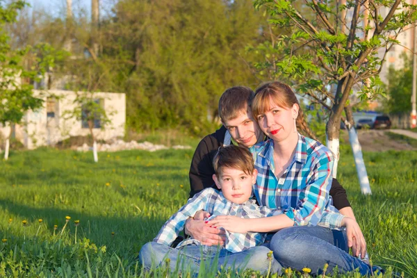 Família sentada na grama no parque — Fotografia de Stock
