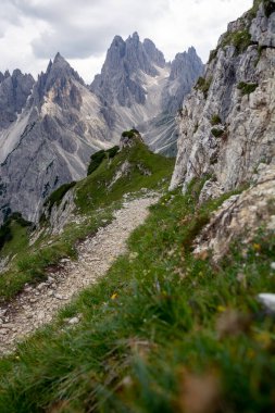 Yazın gün ışığında arka planda kayalık dağların olduğu küçük bir dağ yolu.