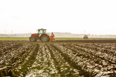 Traktörler karanın zengin topraklarını sürüyorlar.