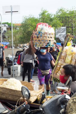 COVID-19 salgını sırasında mal taşıyan bir hamal, bambu sepeti kullanarak yiyecek taşıyor. Fotoğraf: Kumbasari Geleneksel Pazarı, Denpasar Şehri, Bali Eyaleti, Endonezya. Fotoğraf 09 Ekim 2020