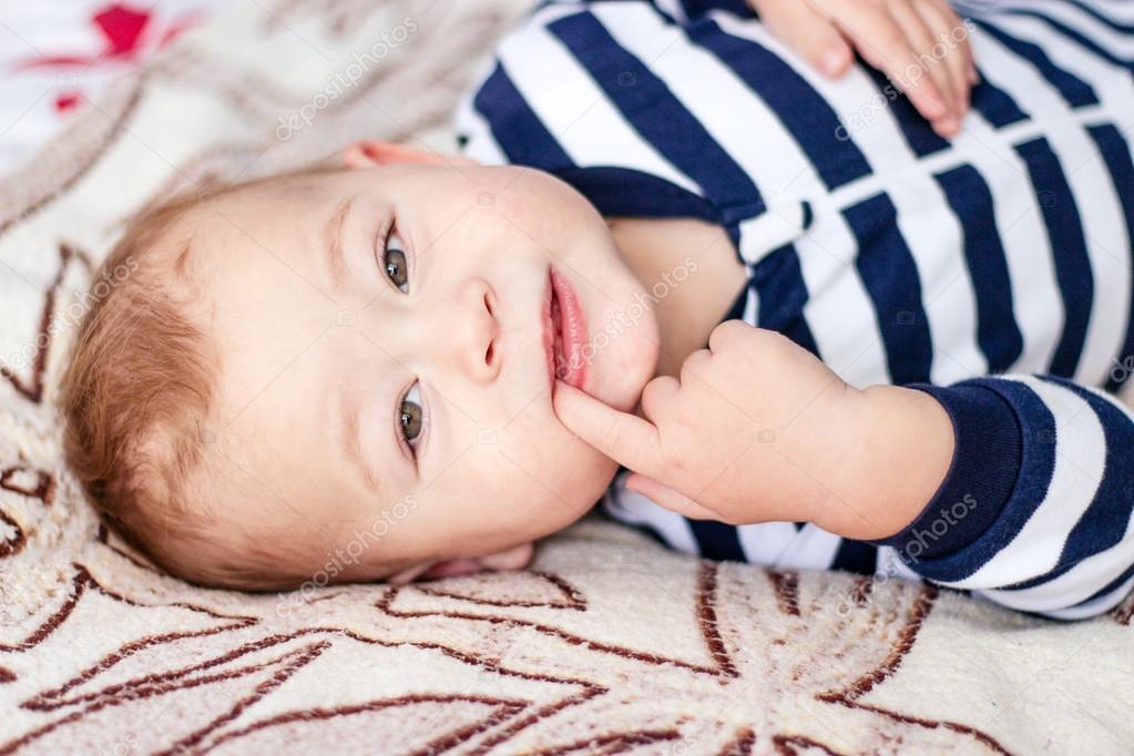 beautiful little boy lying on the bed smiling