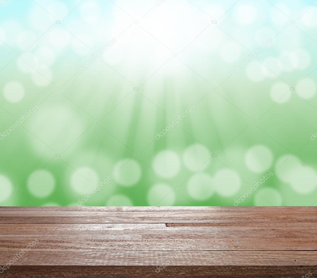 Wood table top on green blurred bokeh light and sun ray