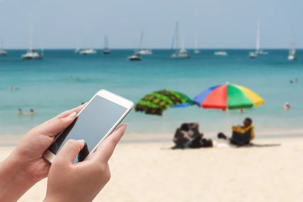 Smartphone üst bulanık mavi denizde kullanarak kadınlar 