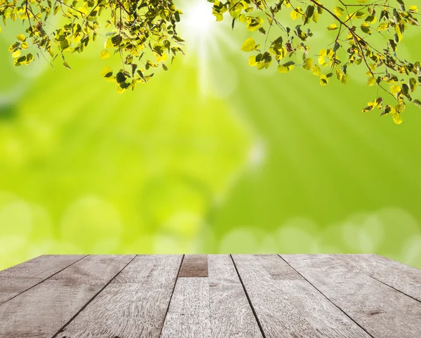Tampo da mesa de madeira na folha verde com bokeh claro — Fotografia de Stock