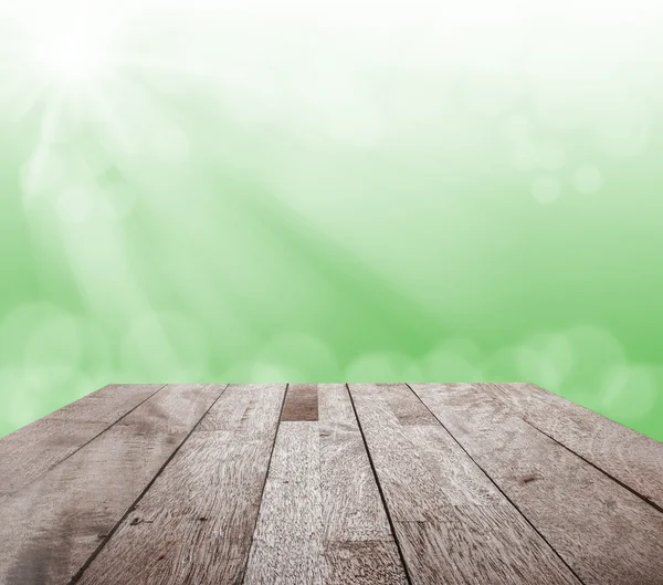 Topo de piso de madeira na luz bokeh borrada verde e raio de sol — Fotografia de Stock