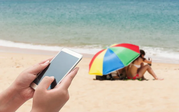 Жінки використовують смартфон зверху на розмитому блакитному морі — стокове фото