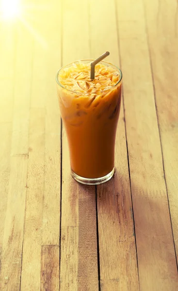 Tè al latte freddo con vetro su sfondo di legno sfocato — Foto Stock