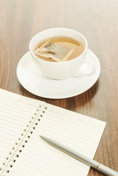 Горячий чай в белой чашке с блокнотом — стоковое фото
