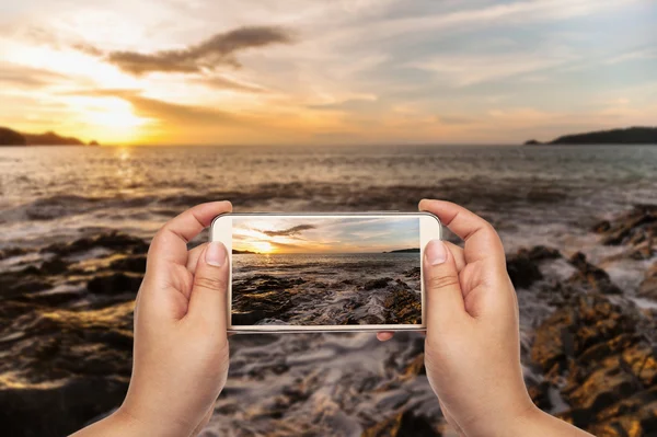 Fotógrafo usando teléfono inteligente en el paisaje marino — Foto de Stock